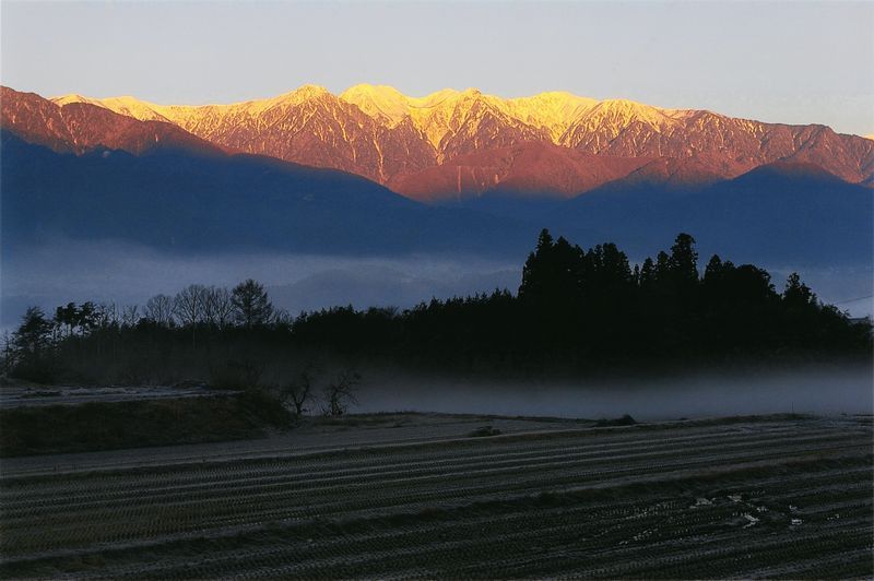 霧がかった山々からの日の出の写真です