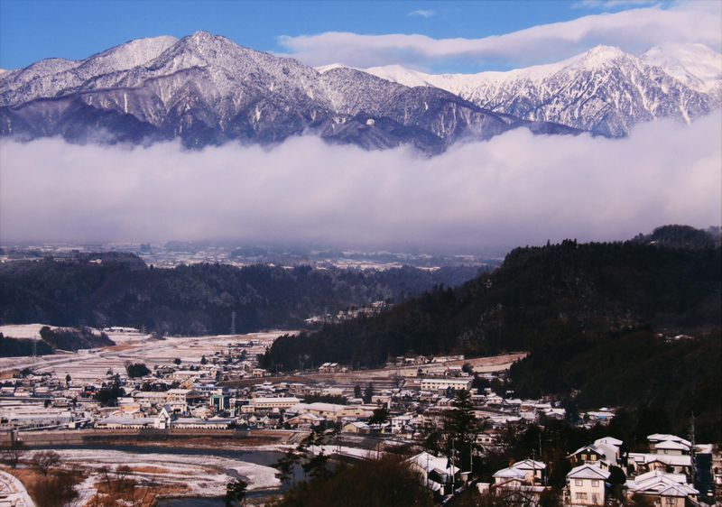 雪がかる中央アルプスと中川村の写真です